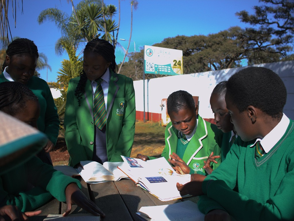 Sixth form pupils studying outdoors at a wooden table